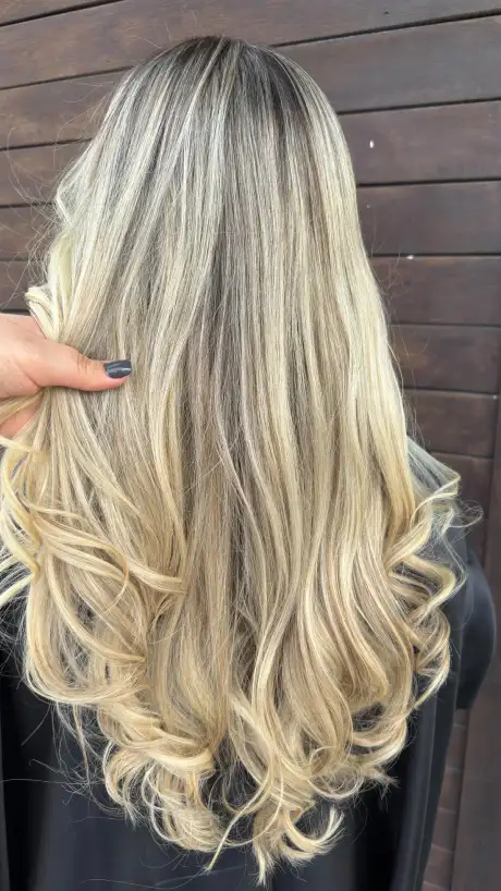 Loiro claro com ondas, a mão da cabeleireira abrindo a mecha